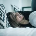 Спете с повдигнати крака на възглавница